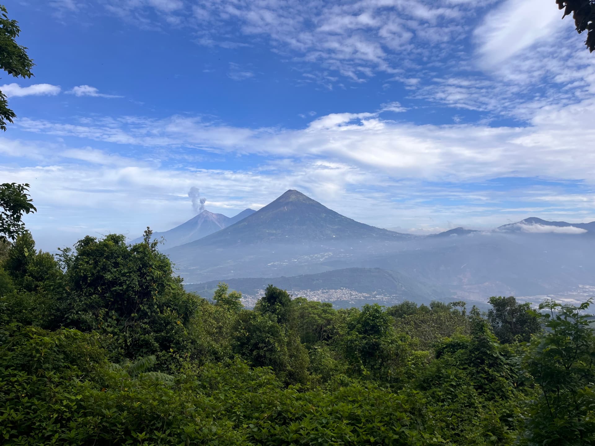 Two volcanic peaks rising above green forest canopy under a bright blue sky, Mexico